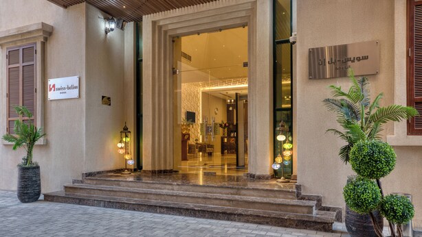 A hotel entrance with a sign reading "Swiss-Bellin DOTA," a glass door, and steps leading up to the entrance. - Swiss-Belinn Doha (Doha)