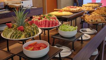 Un buffet con diversi cibi, tra cui anguria, ananas e insalata.