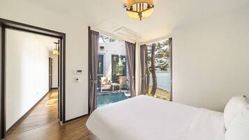 A hotel room with a large bed, a view of a pool and outdoor seating, and a ceiling light fixture.