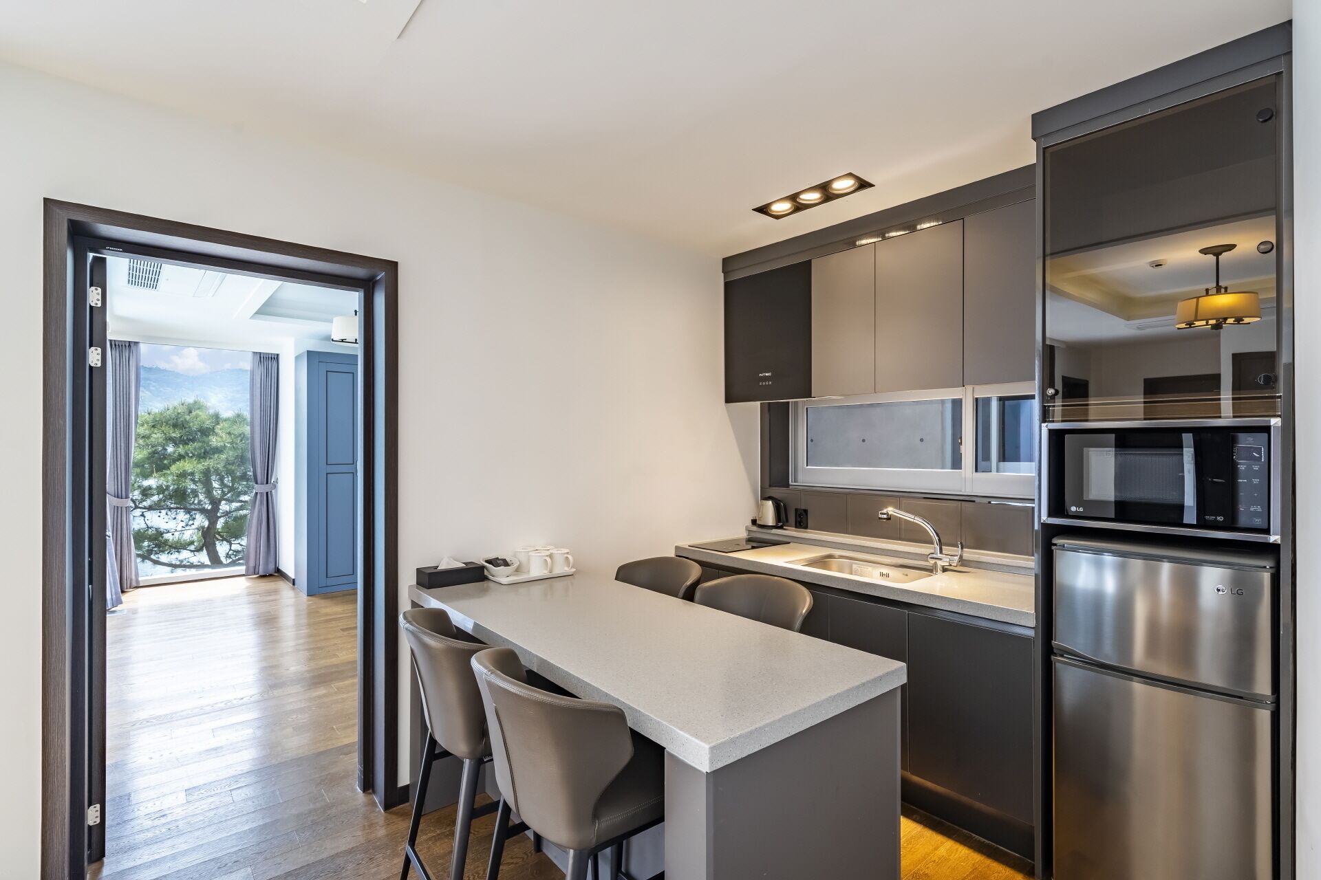 A modern kitchen with a central island, stainless steel appliances, and a view of the outdoors.