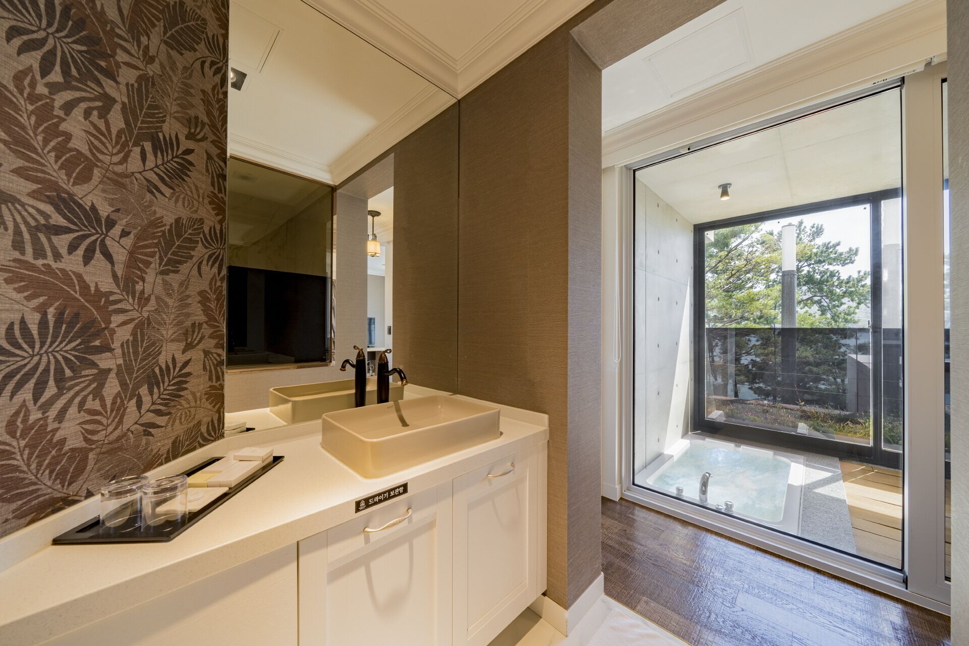 A modern bathroom with a double sink, a large mirror, and a sliding glass door leading to an outdoor area.