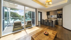 A modern kitchen with a central island, a dining area with a wooden table, and a large sliding glass door leading to a balcony with a pool. - Goseong Hansan Marina Resort (Goseong)