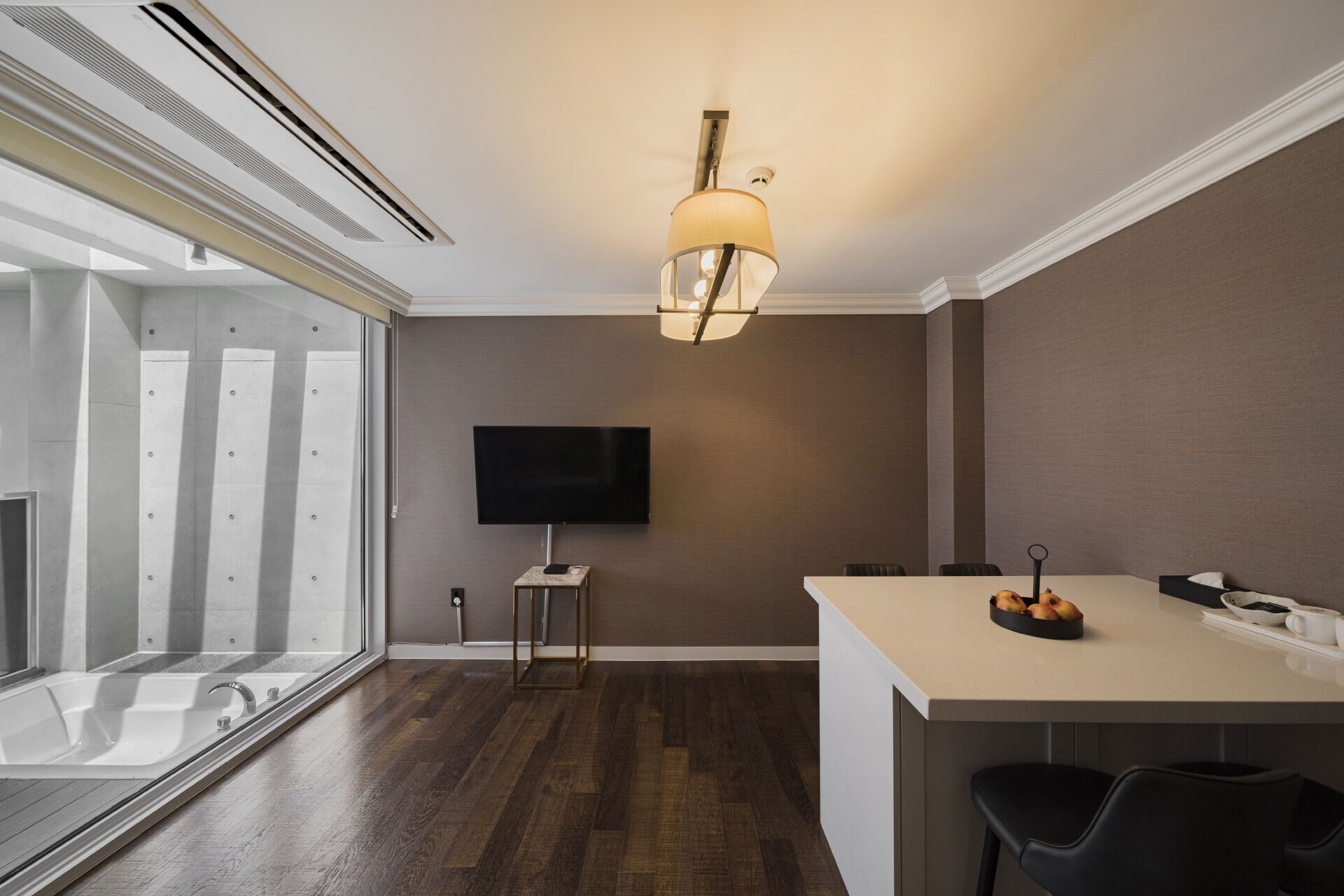 A modern kitchen with a large island, a flat-screen TV, and a pendant light.