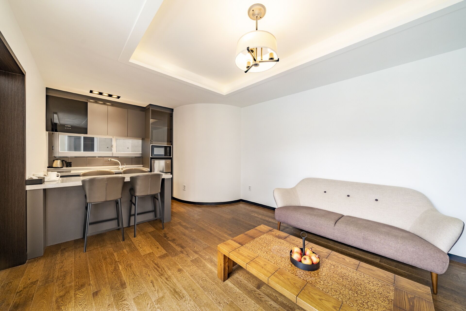 Un espace de vie compact comprenant un coin cuisine, un canapé et une table basse.