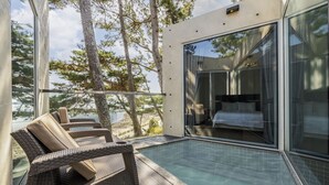 A modern bedroom with a glass door, a pool, and wicker furniture. - Goseong Hansan Marina Resort (Goseong)