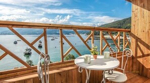 A wooden deck with a table and chairs overlooking a body of water with boats. - Geoje Beach Maru Pension (Geoje)