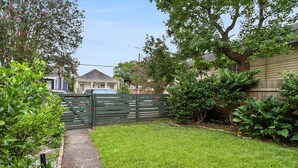 A residential backyard with a wooden fence, a paved path, and various green plants. - Quiet and safe Uptown house steps from Audubon Zoo and shopping on Magazine (New Orleans)