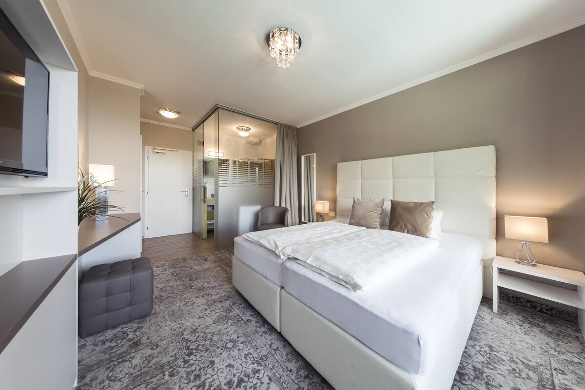 Ein modernes Hotelzimmer mit einem großen Bett, einem Schreibtisch, einem Stuhl und einem Fernseher.