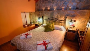 Una cama doble con una colcha estampada, dos almohadas y dos mesitas de noche con lámparas.