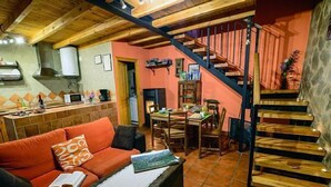 Una sala de estar acogedora con un sofá rojo, una mesa de comedor y una escalera.