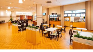 Un restaurante espacioso con numerosas mesas y sillas, una barra con menú a la vista y piso de madera.