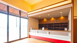 Un área de recepción con mostrador de madera, pared de acento roja y estantería llena de libros.