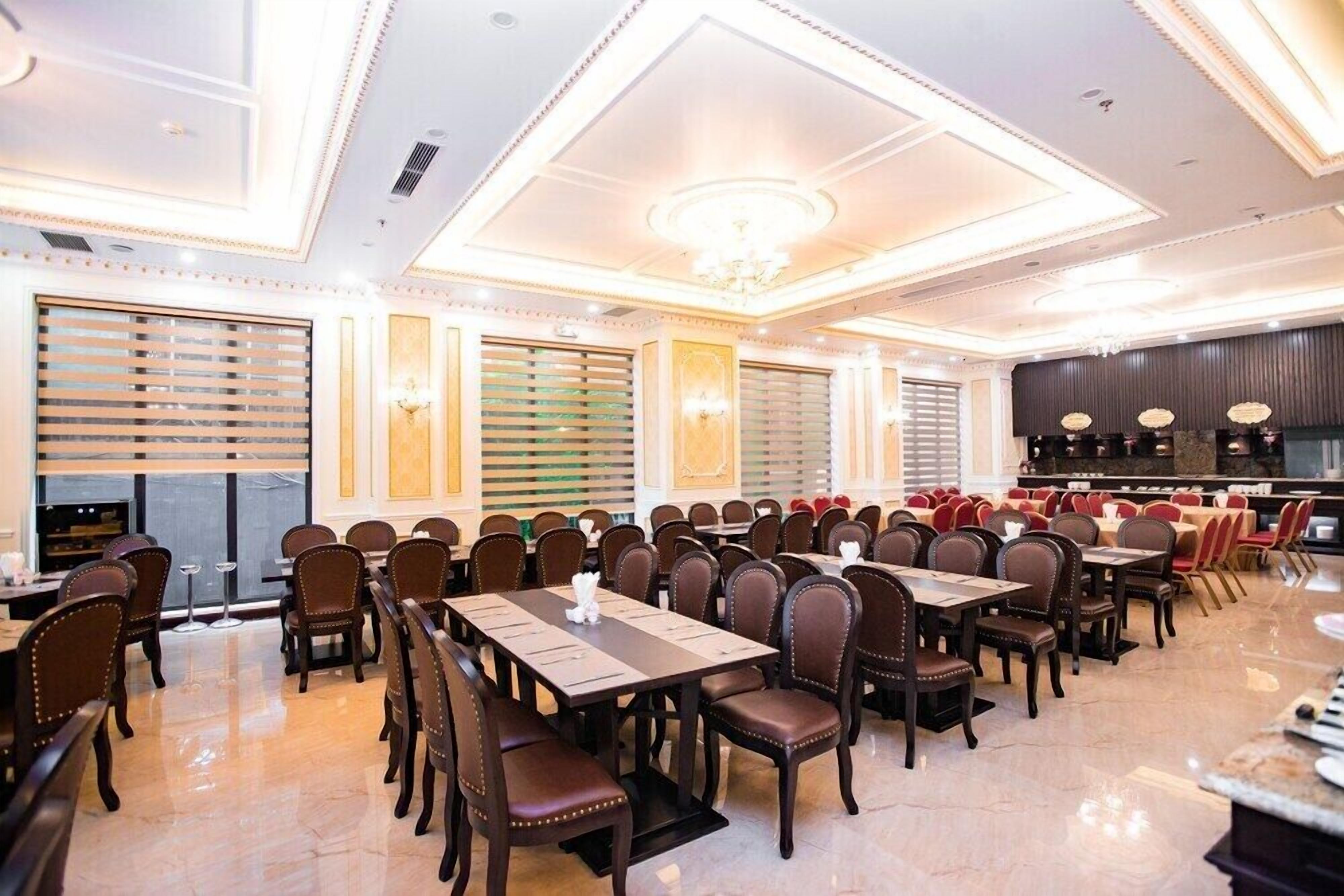 A spacious dining area with multiple tables and chairs, a bar, and a chandelier.