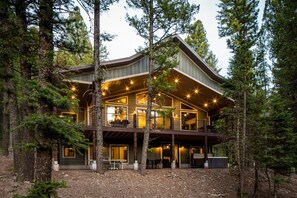 Eine zweistöckige Holzhütte mit Balkon, umgeben von Bäumen.