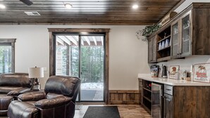 A cozy living area with leather recliners, a coffee table, and a lamp. A sliding glass door leads to a snowy outdoor area.