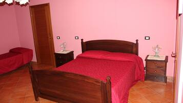 A bedroom with a wooden bed, a red bedspread, a nightstand with a lamp, and a red bench.