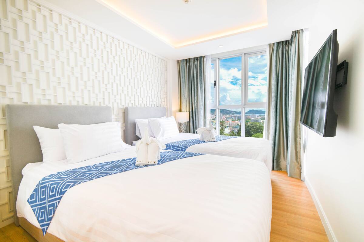 A hotel room with a large bed, a view of the city, and a modern wall design.