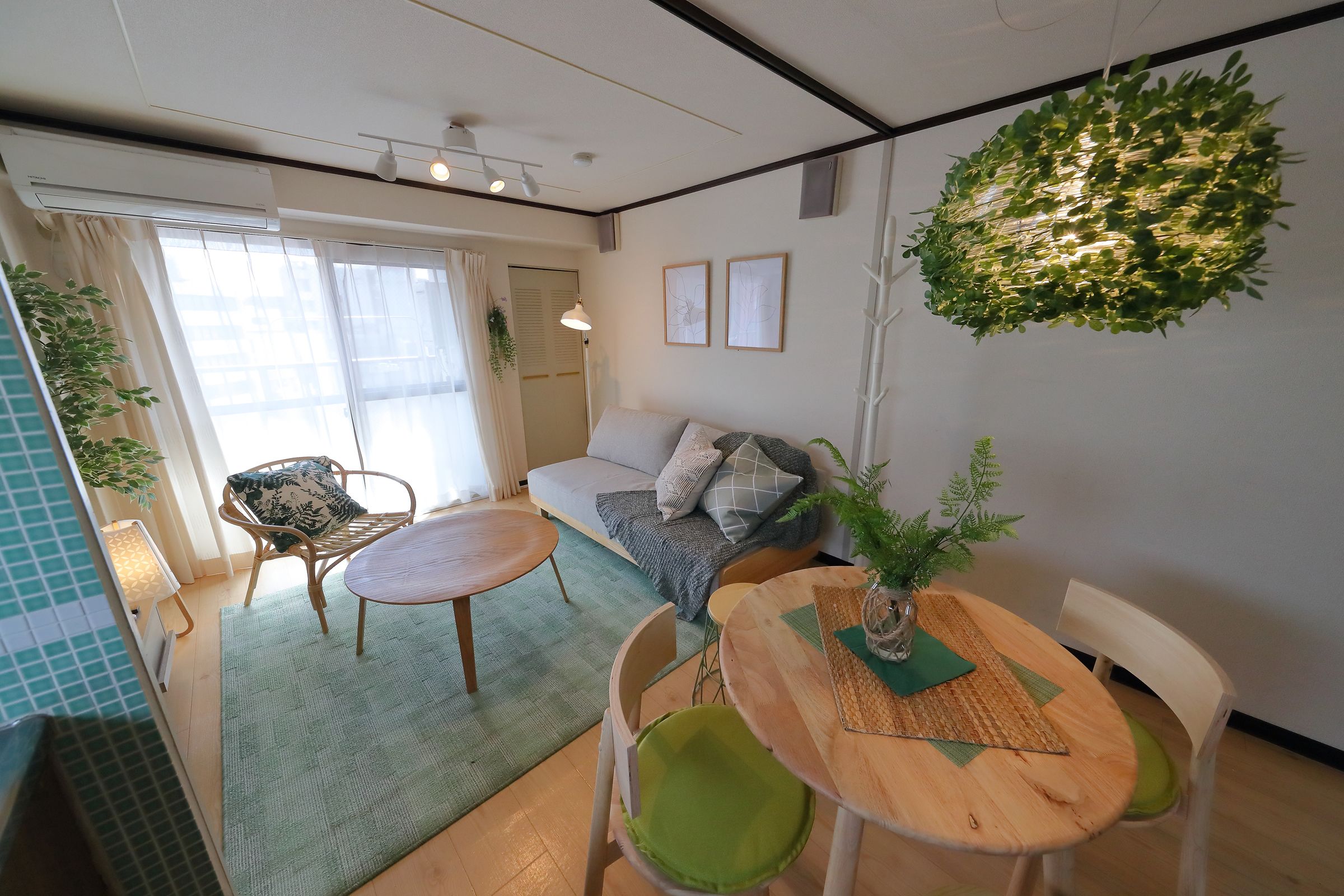 A modern living room with a sofa, two chairs, a wooden table, and a hanging plant.