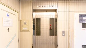 Un ascenseur avec un mur décoré et une pancarte indiquant le Sun Plaza Shitenno House.