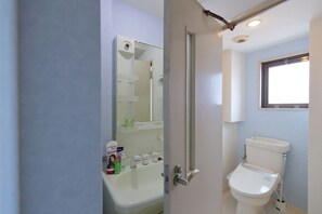 A bathroom with a toilet, a sink, and a mirror. - Onehome Inn Apartment in Tennouji (Osaka)