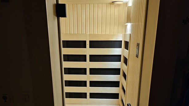 Een smalle, afgesloten ruimte met een houten spijlen deur en een klein raam aan de bovenkant.