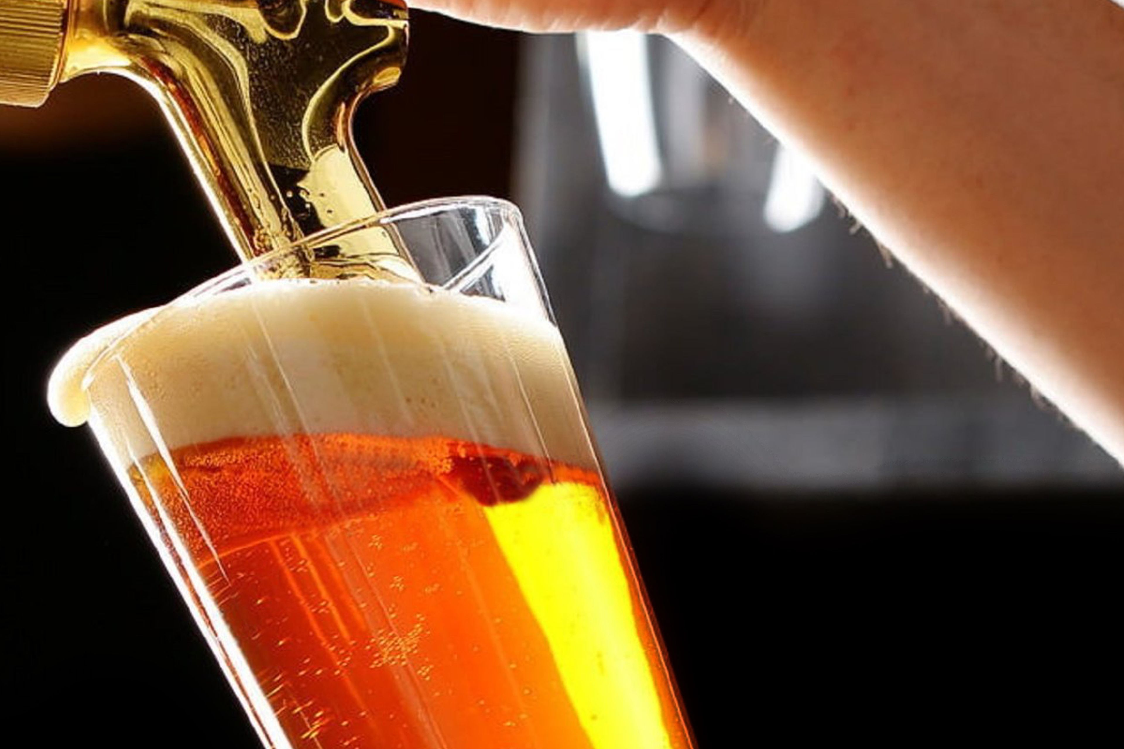 A hand pouring beer into a glass.