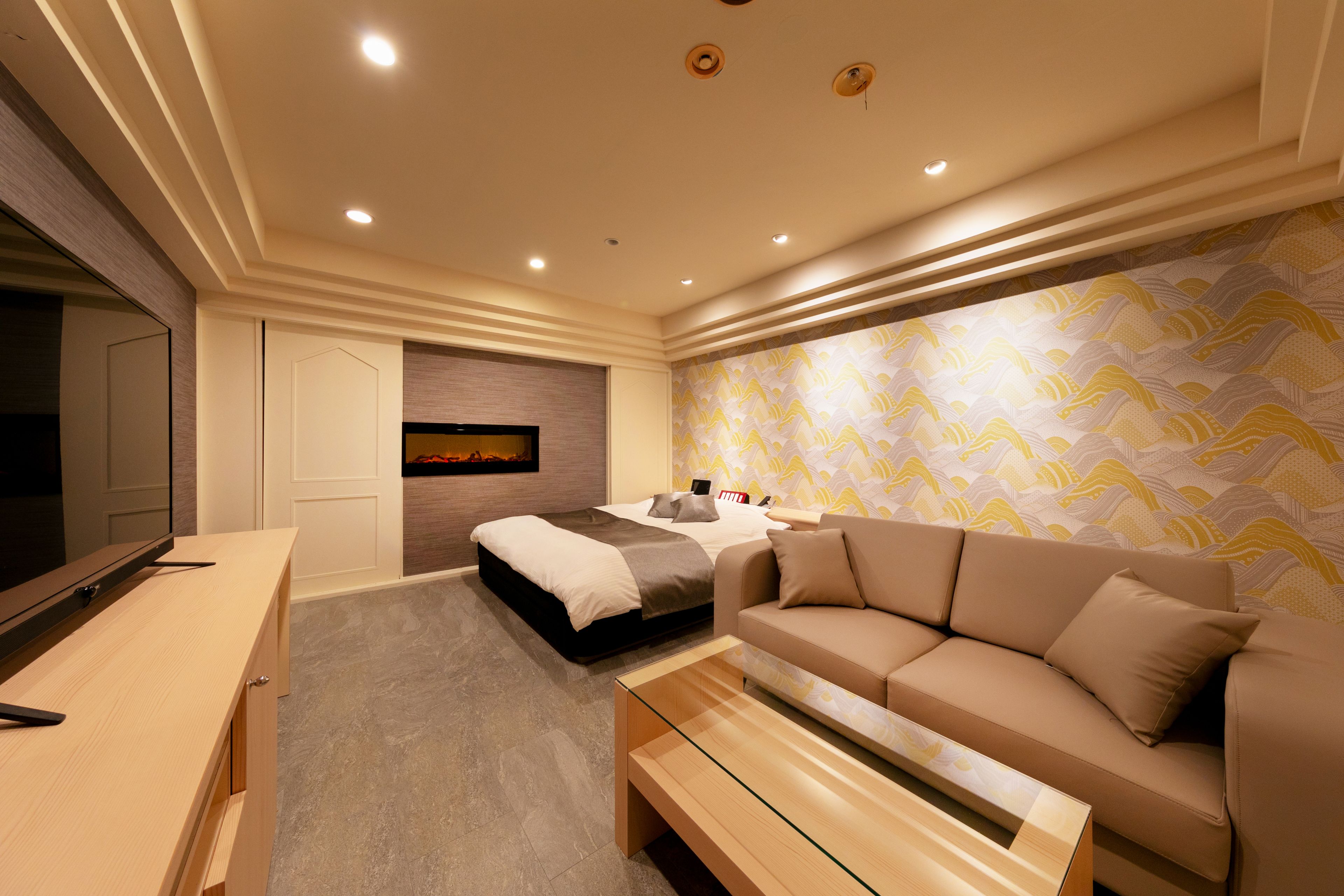 Un dormitorio moderno con cama, sofá, televisión y escritorio.
