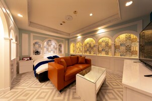 Una habitación de hotel moderna con una cama grande, un sofá, una mesa de centro de vidrio y paneles decorativos en la pared.