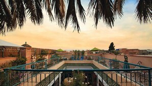 A rooftop terrace with a central staircase, surrounded by greenery and palm trees. - Riad Ambre et Jasmin (Marrakech)