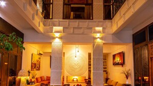 A spacious indoor area with a wooden table and chairs, a decorative wall, and a balcony with railings. - Riad Ambre et Jasmin (Marrakech)