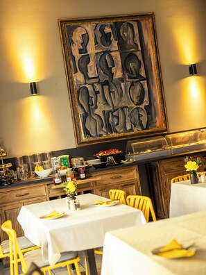 A restaurant interior with tables, chairs, a buffet, and a large abstract painting on the wall. - Hotel Das Nikolai (Munich)