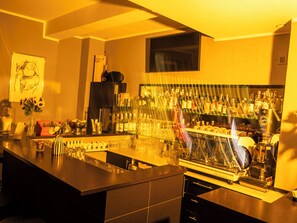 A bar area with a coffee machine, bottles, and glasses. - Hotel Das Nikolai (Munich)