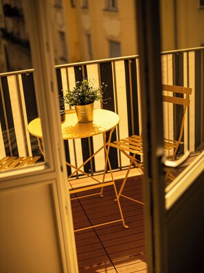 A balcony with a round table, a potted plant, and two chairs. - Hotel Das Nikolai (Munich)