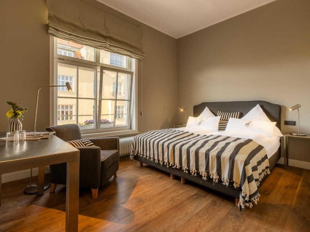 Un dormitorio con cama, escritorio, silla, ventana y radiador.