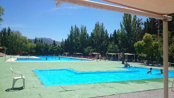 A swimming pool area with multiple pools, lounge chairs, and umbrellas. - Camping & Bungalows Suspiro del Moro (Otura)