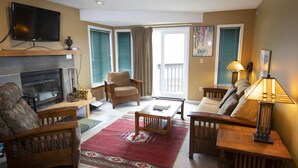 Un salon avec une cheminée, un canapé, une table basse et un téléviseur fixé au mur.