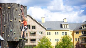 Une personne qui escalade un mur d'escalade en bois, équipé de différentes prises.