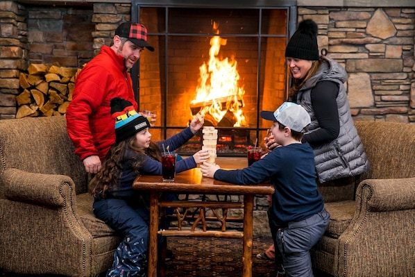 A cozy indoor setting with a fireplace, wooden furniture, and a table where people are seated.