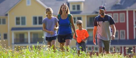 A family walking on a grassy field with houses in the background.