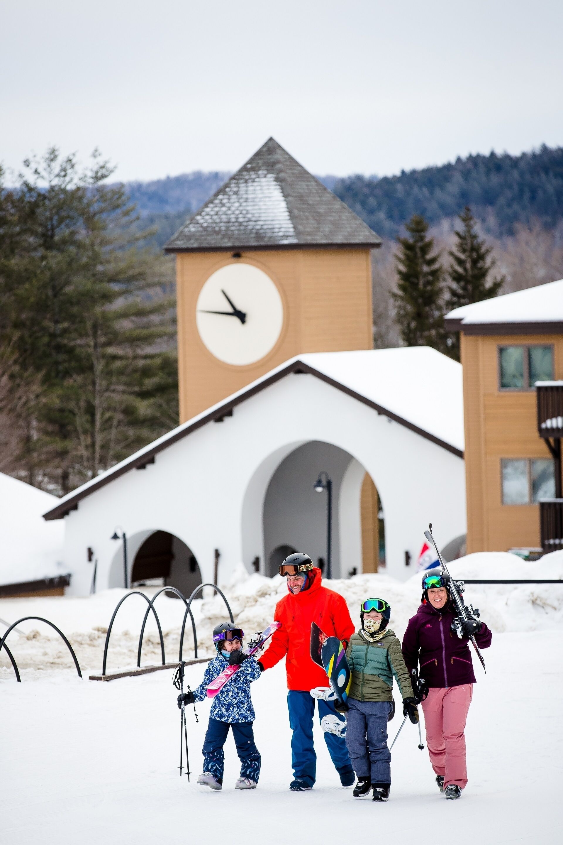 A family walking on a snowy path with a clock tower in the background.