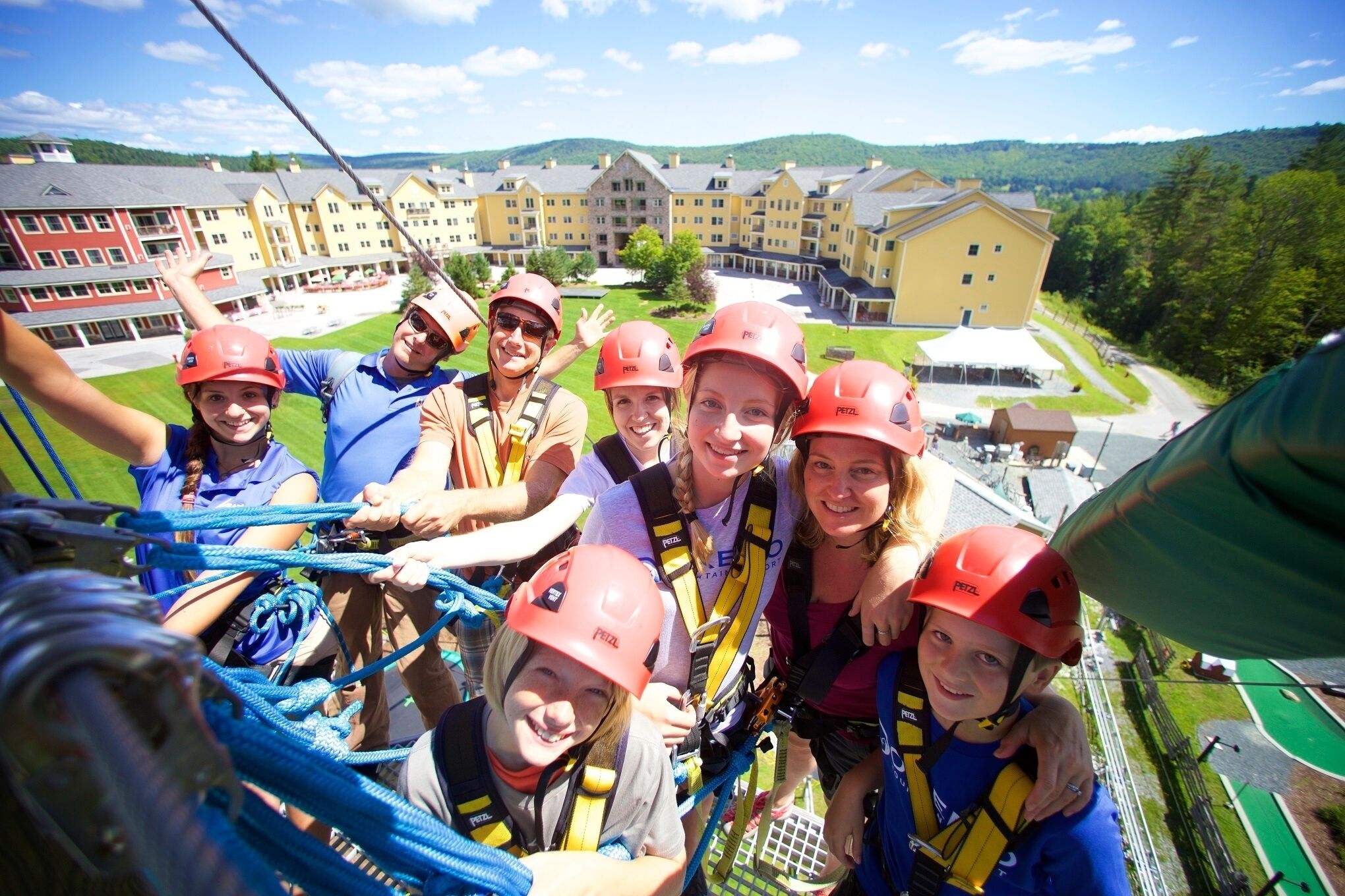 A group of people on a zip line with a large building in the background.