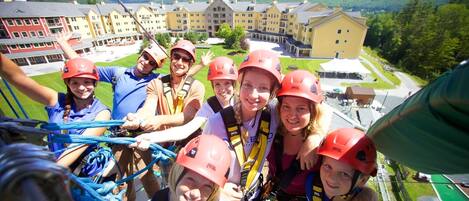 A group of people on a zip line with a large building in the background.