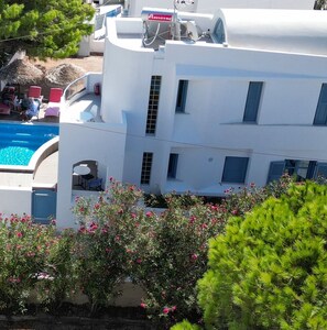 A multi-story building with a pool, outdoor seating, and a view of the surrounding greenery. - Captain Lazaros Villas (Santorini)