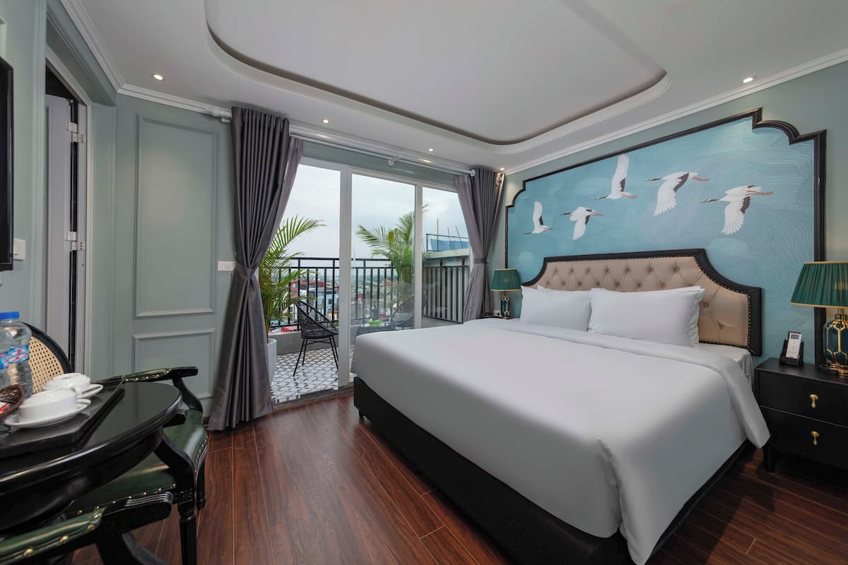 Une chambre d’hôtel avec un grand lit, un balcon offrant une vue agréable et un coin repas avec une table et des chaises.