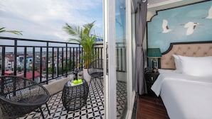 A balcony with a view of the city, a bed with a headboard painting, and a small table with two apples and a bottle. - Madelise Central Hotel & Travel (Hanoi)