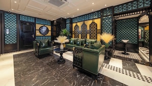 A lobby with a green sofa, a black table, and decorative wall panels. - Madelise Central Hotel & Travel (Hanoi)