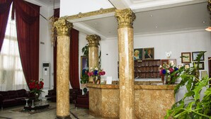 A lobby with marble columns, a reception desk, and a seating area with a sofa and armchairs. - Bougainvillea Hotel (Port Harcourt)