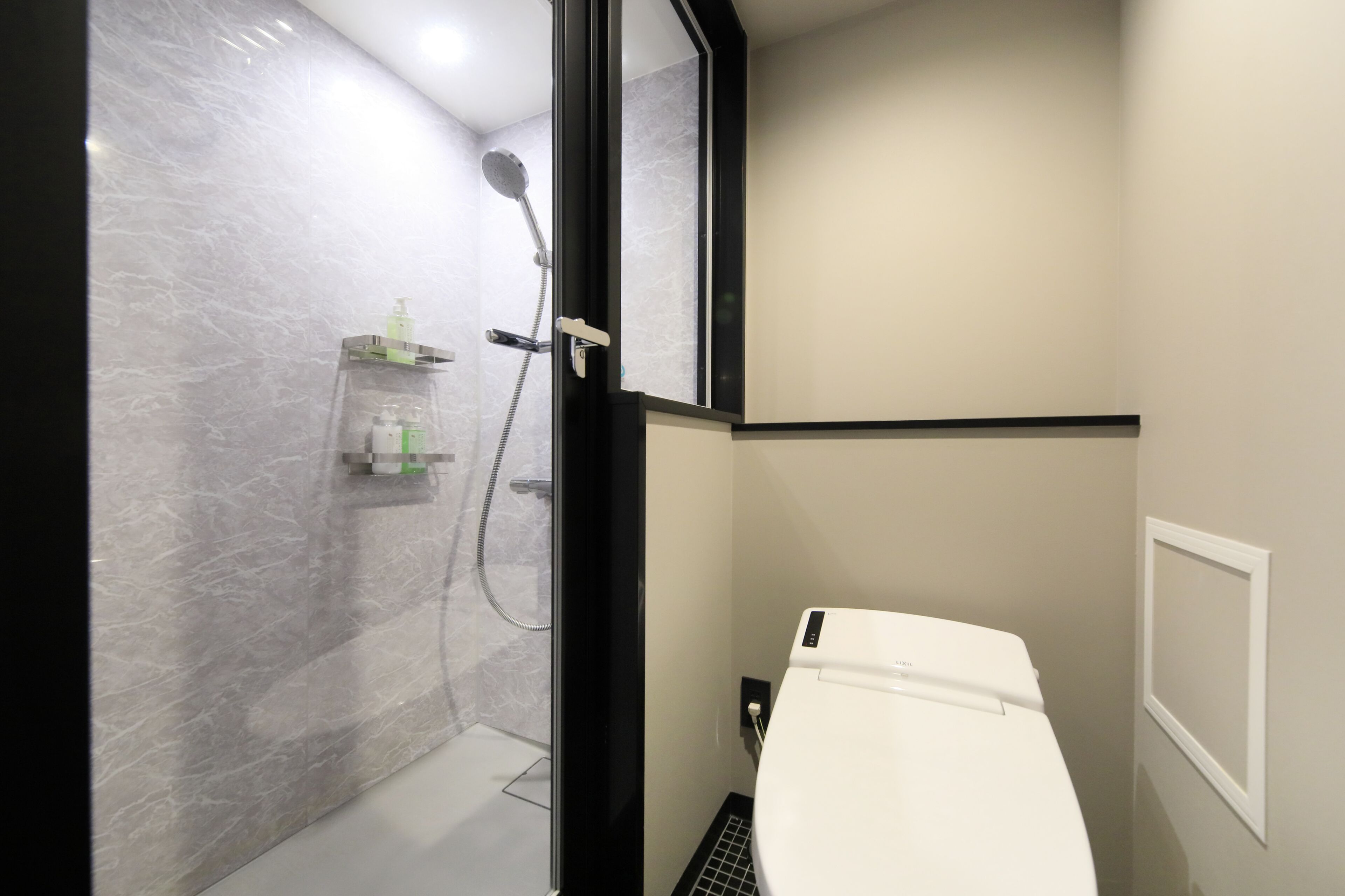 A modern bathroom with a shower, toilet, and a glass-enclosed shower area.