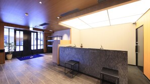 A reception area with a marble counter, two black stools, a potted plant, and a large window. - Quintessa Hotel Fukuoka Hakata Relax&Sleep (Fukuoka)
