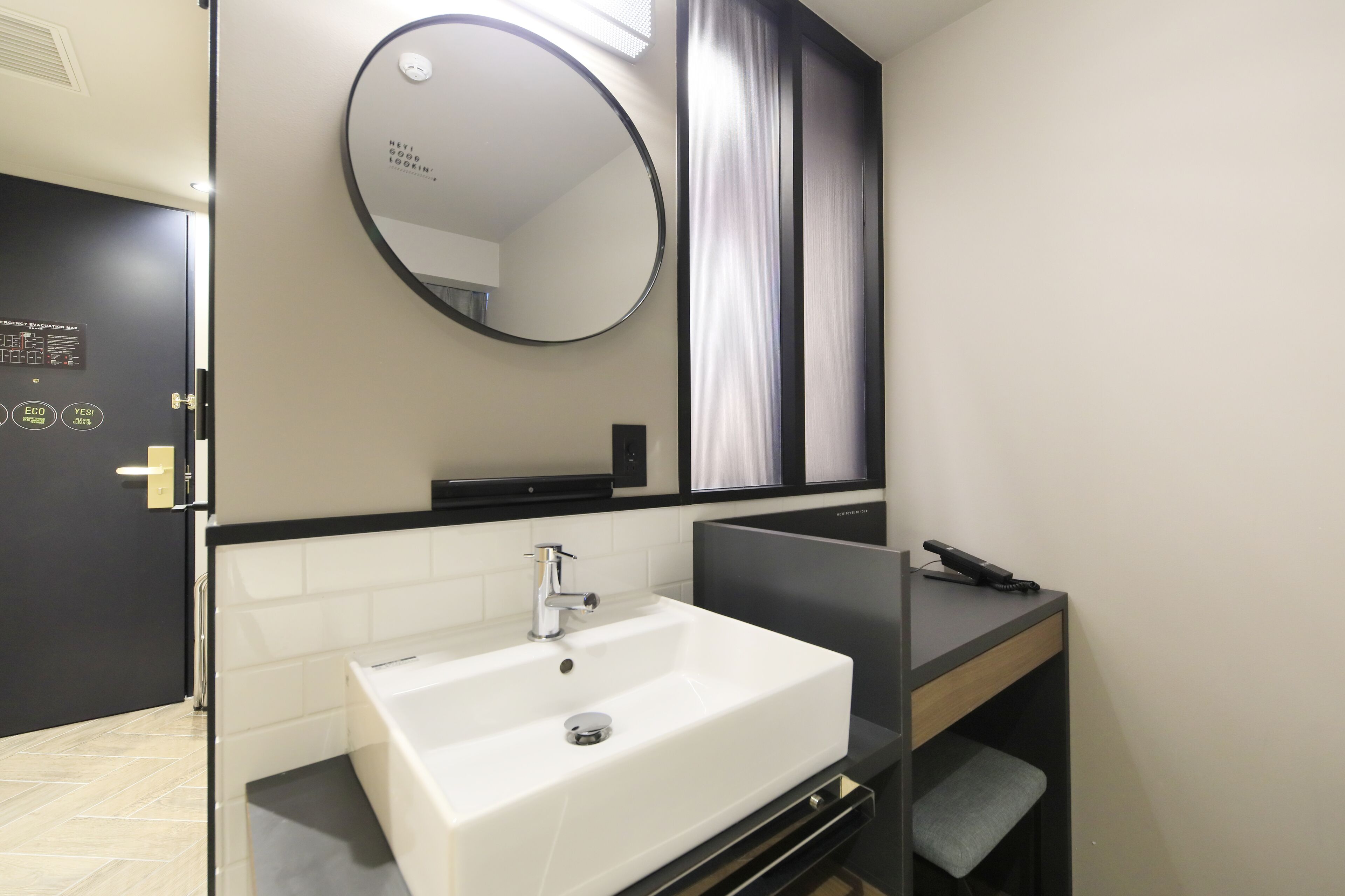 Un bagno moderno con un lavandino bianco, uno specchio rotondo e un mobile contenitore nero.